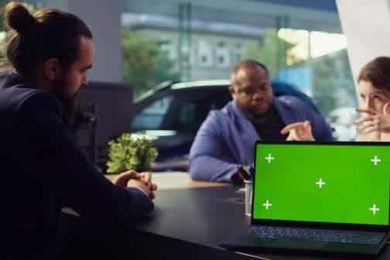 Business meeting with diverse team and green screen laptop display.