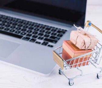 Mini shopping cart with gifts by laptop