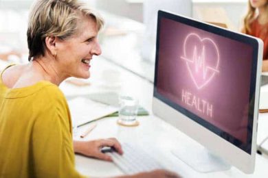 Smiling woman viewing health information on a computer screen.