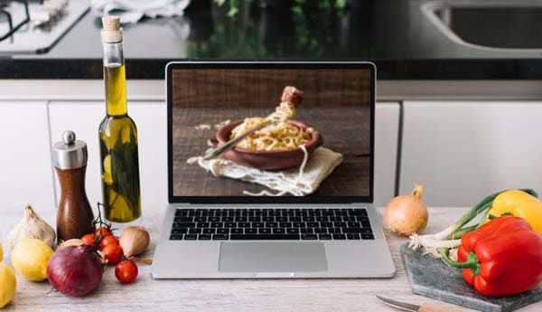 Cooking ingredients next to a laptop in kitchen.