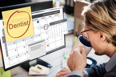 Man planning dentist appointment on computer calendar.