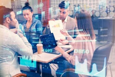 Diverse business team reviewing digital data and charts.
